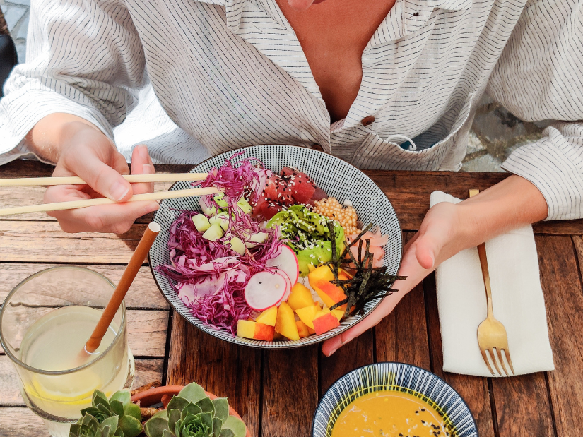 Woman wearing a pinstriped blouse enjoying a healthy bowl full of prebiotic and probiotic rich foods.